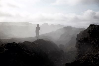 Person standing on mountain against sky