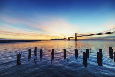 Pier in sea at sunset