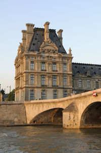 Arch bridge over river against buildings in city