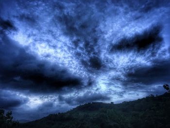 Low angle view of storm clouds over silhouette landscape