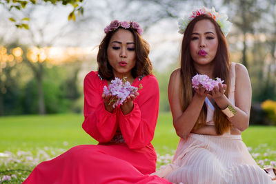 Portrait of happy female friends with flowers on the background