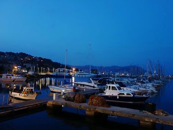 Boats moored at jetty against clear blue sky