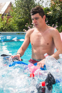 Full length of shirtless man holding swimming pool