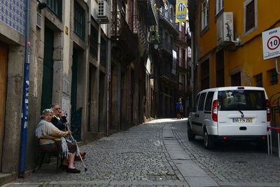 Man sitting on street amidst buildings in city