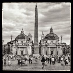 Tourists in front of church against cloudy sky