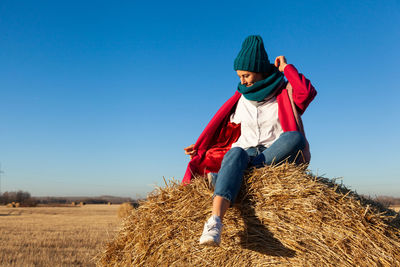 Portrait of a beautiful young model in blue knitted hat and warm clothes have fun, sitting