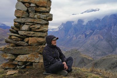 Man sitting on rocks against mountains