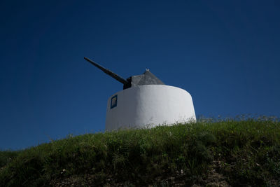 Low angle view of windmill on field against clear blue sky