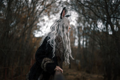Woman standing amidst trees in forest during winter