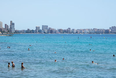 People enjoying in sea against clear sky