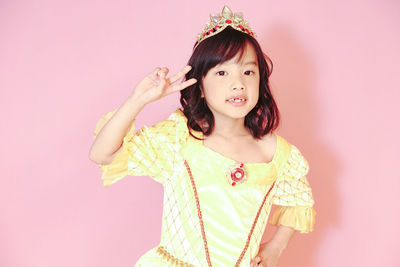 Portrait of happy girl standing against pink background