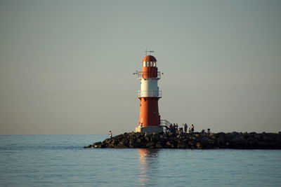 Lighthouse by sea against sky