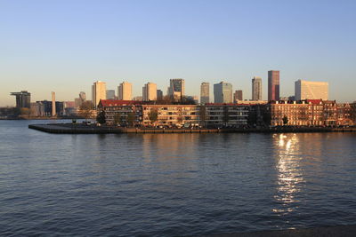 Sea by cityscape against clear sky