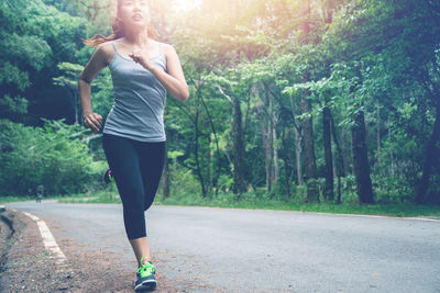 Full length of young woman running on road