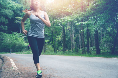 Full length of woman running on road against sky