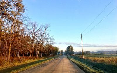 Road by trees against clear sky