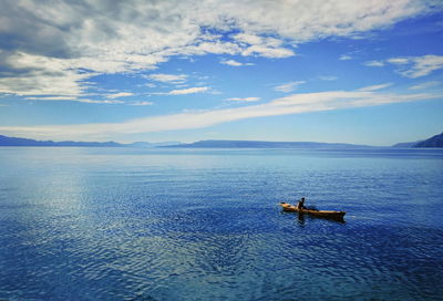 High angle view of man sitting in boat on sea against sky