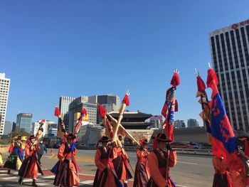 People at amusement park against sky in city