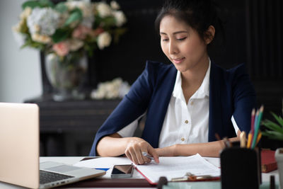 Woman using phone while sitting on table