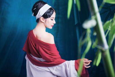 Young woman standing against blue curtain