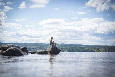 Boy sitting on rock at sea