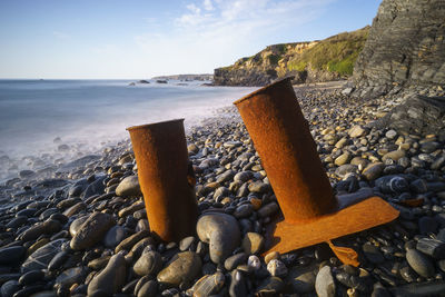 Rocks on shore at beach against sky