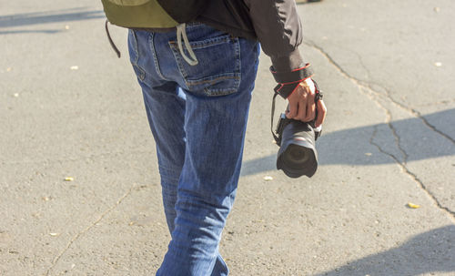 Midsection of man walking on road with camera