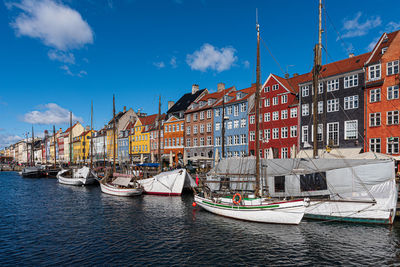 Sailboats moored on canal by buildings against sky in city