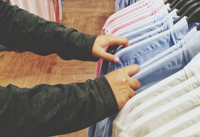 Cropped hands of person choosing shirts in store