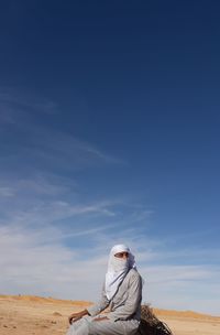 Man sitting on land against sky