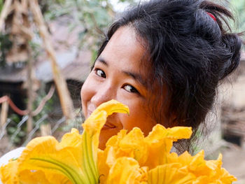 Close-up portrait of woman holding yellow flower