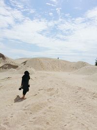 Rear view of woman walking in desert