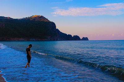 Man on beach against sky during sunset