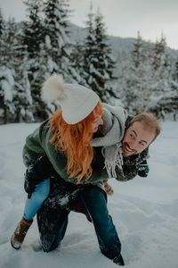 Couple embracing while standing on snow covered land