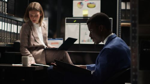 Rear view of man using digital tablet while sitting in office