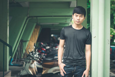 Portrait of young man standing against wall