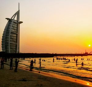 Silhouette people on beach against clear sky during sunset