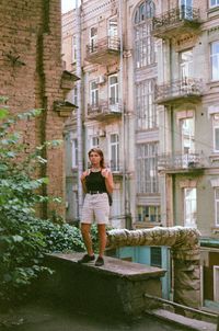 Full length of woman standing against building in city