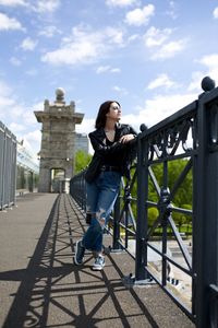 Low angle view of woman standing on bridge against sky