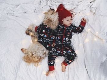 High angle view of cute child sleeping with dog on bed at home