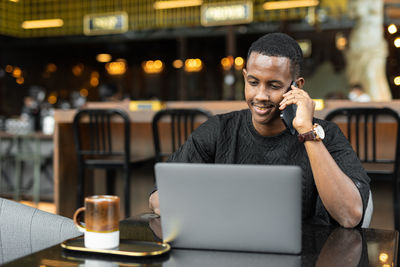 Young man using laptop at cafe