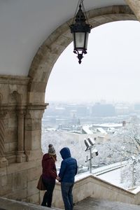 Rear view of people standing in city during winter