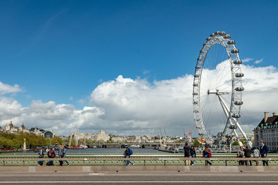 People in amusement park against sky in city