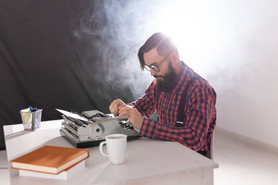 Young man using smart phone while sitting on table