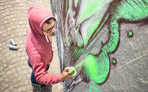 Full length of man making graffiti on wall