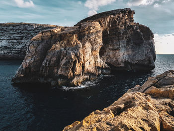 Rock formation in sea against sky