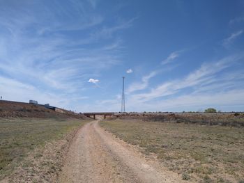 Road amidst field against sky