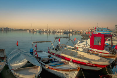 Boats moored in harbor at sunset