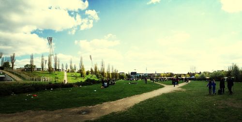 People on grass against cloudy sky