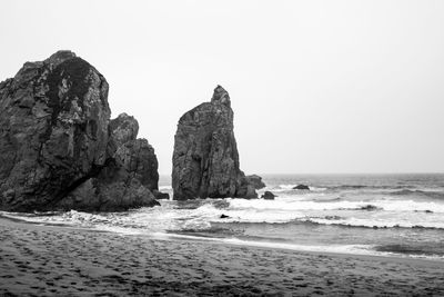 Rock formation on beach against clear sky